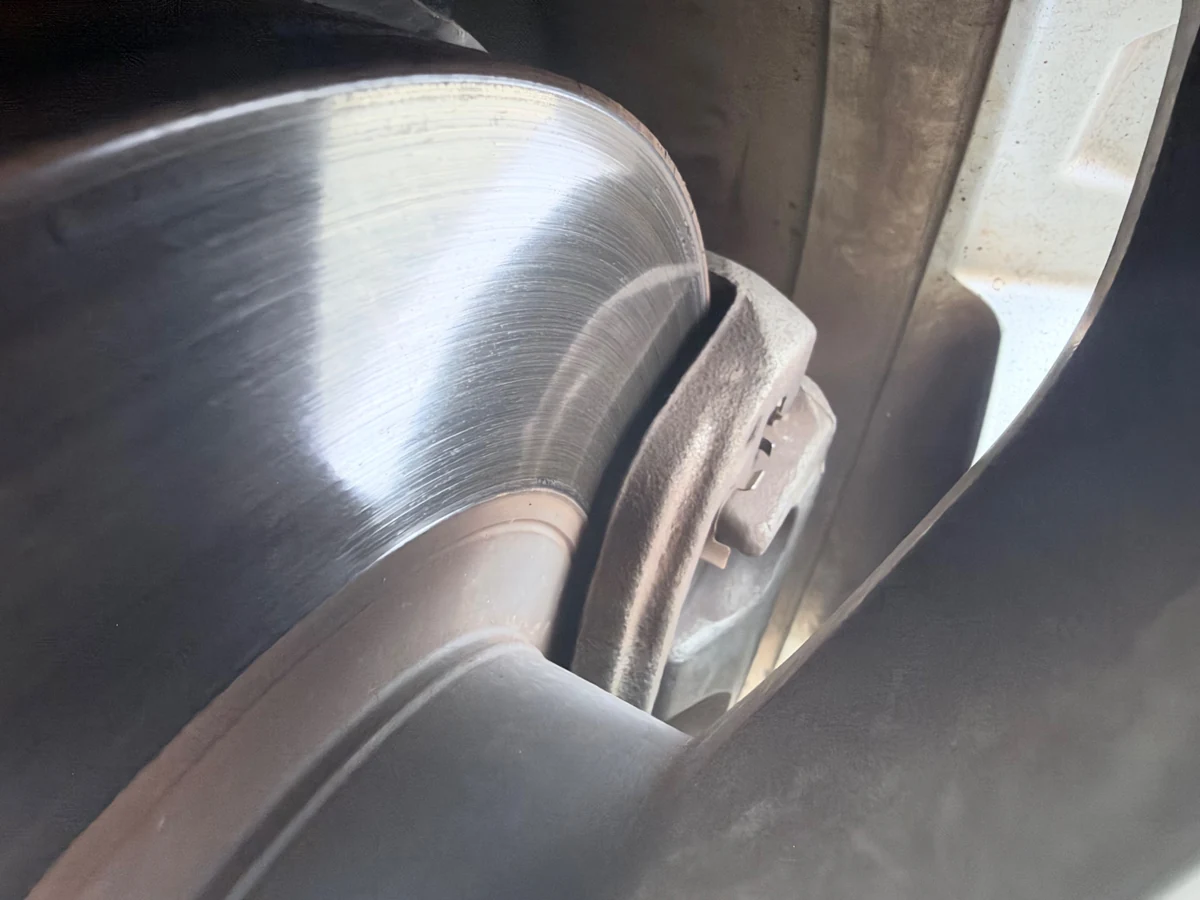 Close-up of a brake rotor and caliper photographed through a Forester wheel