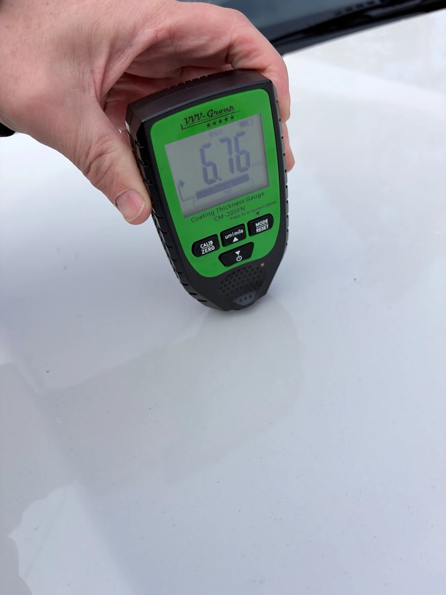 Paint-thickness gauge displaying 6.76 mils on the Forester hood